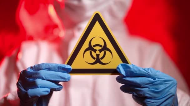 Infectionist Doctor in een beschermend pak toont een biologisch gevarenbord - Video