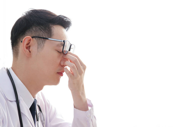 Aasialaiset mieslääkärit ovat stressaantuneita potilaiden hoidosta, käyttäen käsiä nenän hierontaan stressin lievittämiseksi ja rentoutumisen helpottamiseksi. Valkoinen tausta. kopioi tila - Valokuva, kuva