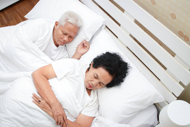 Azjatycka para starców śpi w łóżku w sypialni. Starsze koncepcje zdrowotne, choroby, emerytury. przestrzeń kopiowania - Zdjęcie, obraz