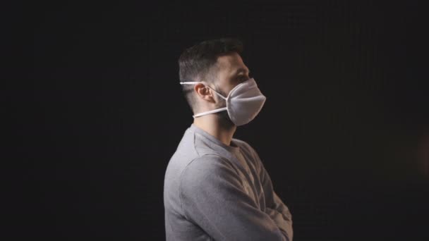 Zijaanzicht van de mens met gezichtsmasker wijzer naar camera, geïsoleerd op zwarte achtergrond - Video