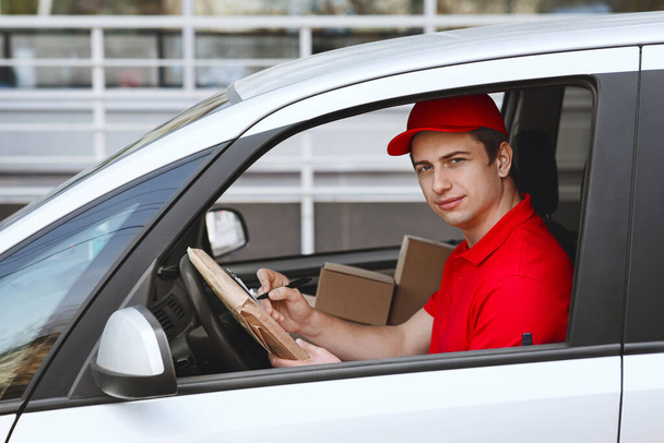 Timely home delivery by car. Courier in auto makes entry in tablet - Photo, Image
