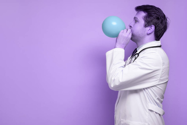 Portret młodego mężczyzny dmuchającego balon na białym tle - Zdjęcie, obraz