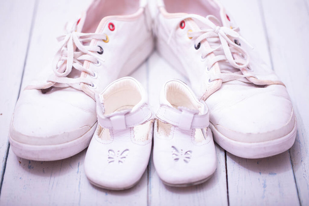 Tatínkovy dětské tenisky, na bílém dřevěném pozadí, koncept na Den otců. - Fotografie, Obrázek
