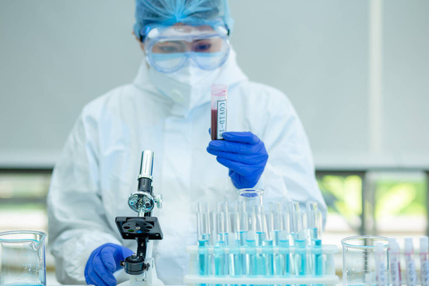 Επιστήμονας ή ερευνητής παραδίδει μπλε γάντια που κρατούν γρίπη, ιλαρά, κορωνοϊό, νόσο του covid-19 για την προετοιμασία της ανθρώπινης κλινικής δοκιμής εμβολιασμός, φάρμακα και φάρμακα. - Φωτογραφία, εικόνα