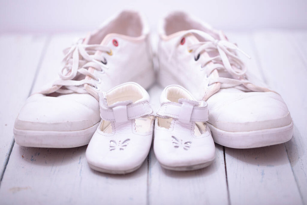 Zapatillas de deporte del bebé de papá, sobre fondo de madera blanca, concepto de día de los padres
. - Foto, imagen