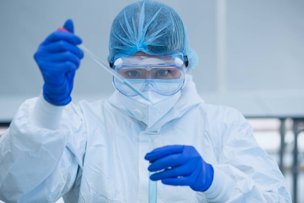 Scientist or researcher hand in blue gloves holding flu, measles, coronavirus, covid-19 vaccine disease preparing for human clinical trials vaccination shot, medicine and drug concept. - Photo, Image