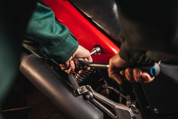 Close-up male hands with wrenches. Auto mechanic works in the garage. Repair service. Motorcycle repair. - Photo, image