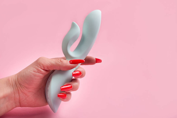 el Consolador en la mano sobre un fondo rosa, juguete sexual
 - Foto, Imagen