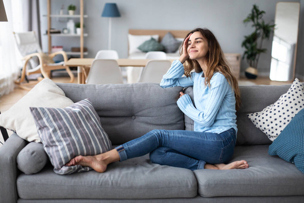 Tranquil smiling millennial woman leaning on sofa. Domestic life. - Fotografie, Obrázek