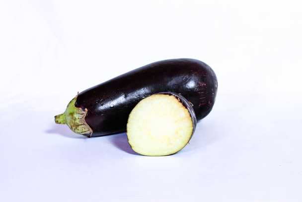 aubergine fraîche entière et coupée en deux sur fond blanc, aubergine. thème aliments, ingrédients, santé, légumes
 - Photo, image