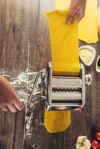 Zubereitung hausgemachter Pasta mit Nudelmaschine auf Holztisch. - Foto, Bild