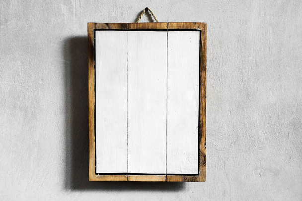 Белая деревянная пустая доска висит на серой бетонной стене. Место для логотипа, знака или текста
. - Фото, изображение
