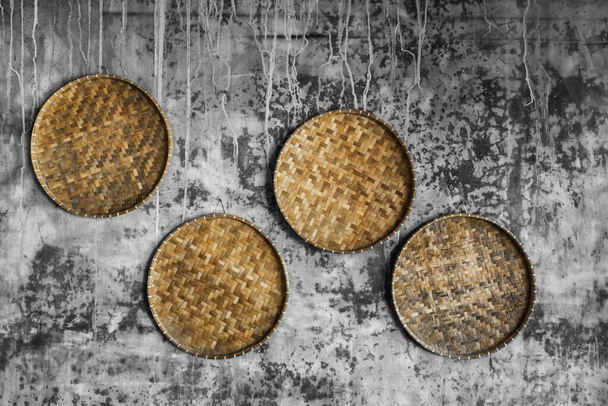 Gray shabby betonnen muur versierd met rieten handgemaakte ronde trays. Eco-stijl en concept, Marokkaanse cultuur. Hipster cafe ontwerp. - Foto, afbeelding