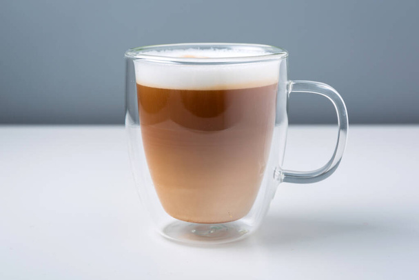 Latte coffee in the glass mug on the table - 写真・画像
