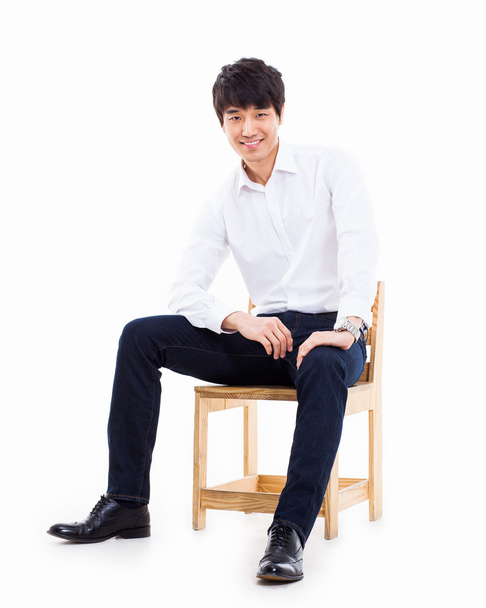 fiatal ázsiai ember ül a széken. - Fotó, kép