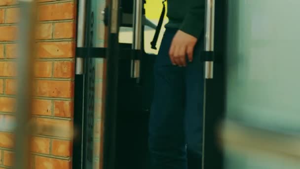 Un hombre con jeans azules sale de la puerta de un estudio de grabación
 - Metraje, vídeo