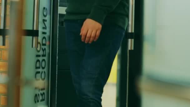 Un hombre con jeans azules sale de la puerta de un estudio de grabación
 - Metraje, vídeo