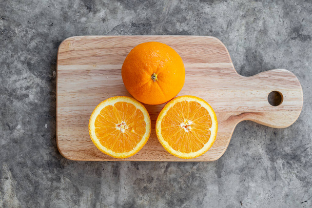 Entier et tranché d'orange avec planche à découper sur table en béton gris, vue de dessus
 - Photo, image