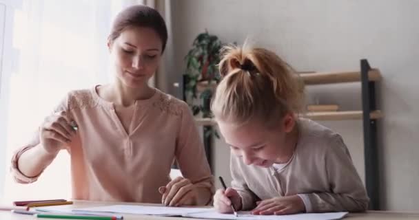 Smiling young mother drawing pictures in album with daughter. - Video, Çekim