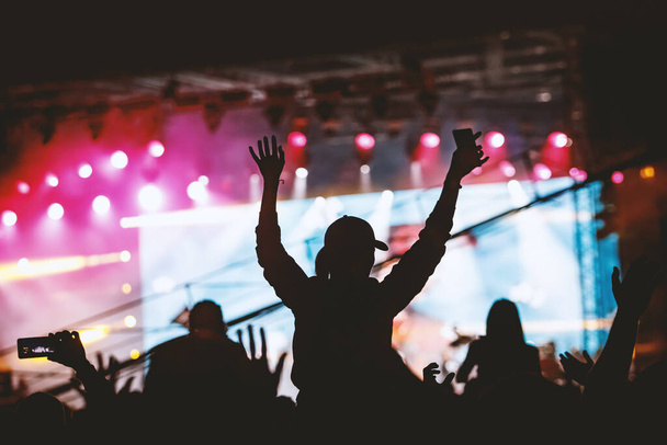 Siluetas de personas con las manos levantadas en un concierto. Luz de escenario
 - Foto, imagen