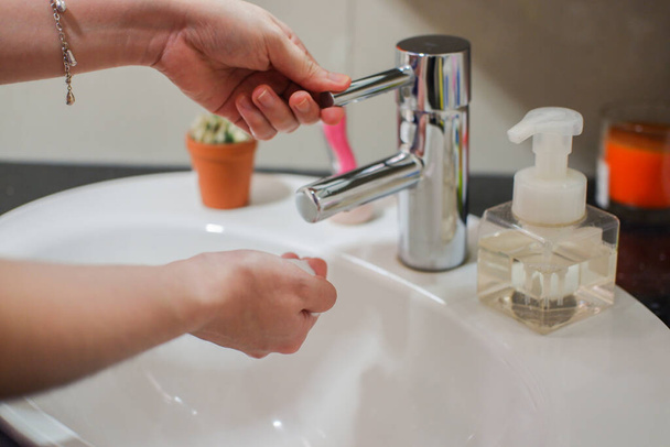 Azjatka o jasnej skórze spłukuje ręce w umywalce. Wykazuje higienę i czystość w zapobieganiu rozprzestrzenianiu się wirusa lub bakterii - Zdjęcie, obraz