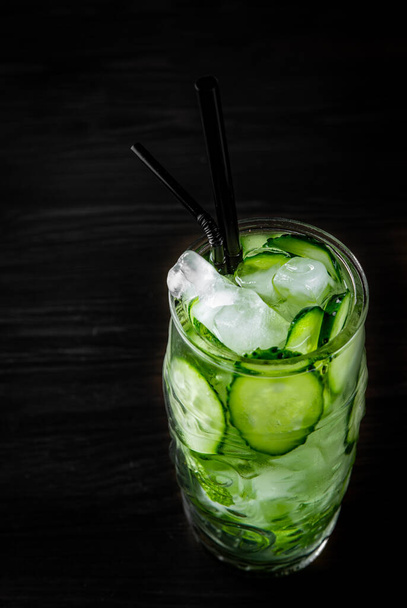 cucumber and mint lemonade in a glass on black wooden table background - Fotó, kép