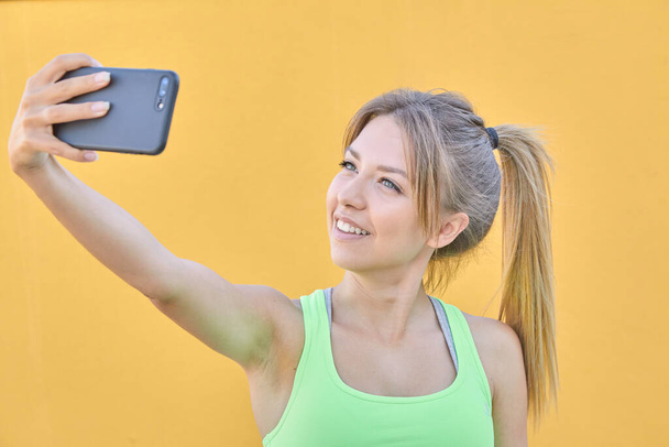 Kaunis blondi tyttö tekee selfien matkapuhelimellaan. - Valokuva, kuva
