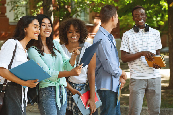 Estudantes alegres universitárias verificando o horário das aulas enquanto estão ao ar livre
 - Foto, Imagem