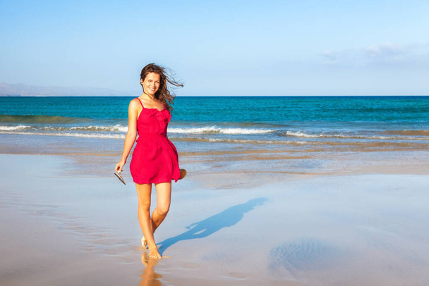 Young woman in red dress enjoying the beach - Foto, imagen