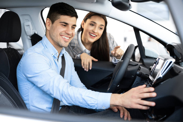 Ehefrau hilft Ehemann bei der Wahl eines neuen Autos im Autohaus - Foto, Bild