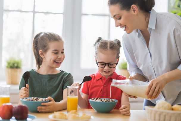 Healthy food at home. Happy family in the kitchen. Mother and children daughters are having breakfast. - Foto, imagen