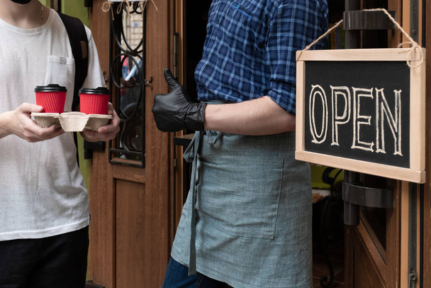 Mãos de garçom segura duas xícaras de café perto da porta de abertura do café. Trabalhador dá uma ordem tirar para o cliente do mercado de rua
. - Foto, Imagem