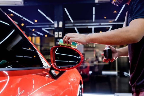 Car service worker applying nano coating on a car detail - 写真・画像