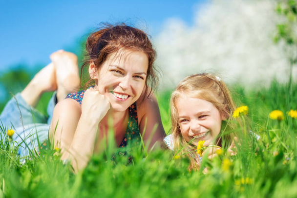 Young woman and her daughter on green summer grass - Fotografie, Obrázek