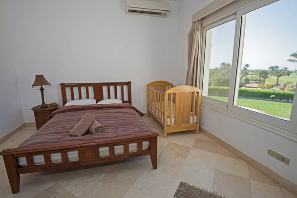 Εσωτερική διακόσμηση επίπλωση πολυτελούς show home double bedroom με βρεφική κούνια και θέα στον κήπο - Φωτογραφία, εικόνα