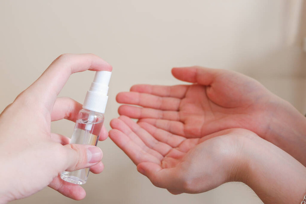 Light-skinned Asian woman pumping a hand sanitizer spray bottle to another hand. Shows hygiene and cleanliness for virus or bacterial spread prevention - Fotó, kép