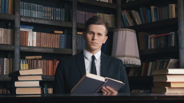 Portret van een aantrekkelijke zakenman die een boek leest in de bibliotheek denkend over het genereren van ideeën. - Video