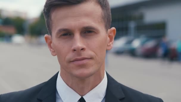 Close up attractive man in business suit in looking into camera in the city outdoors. Portrait of confident male businessman standing outdoor near offices. - Footage, Video