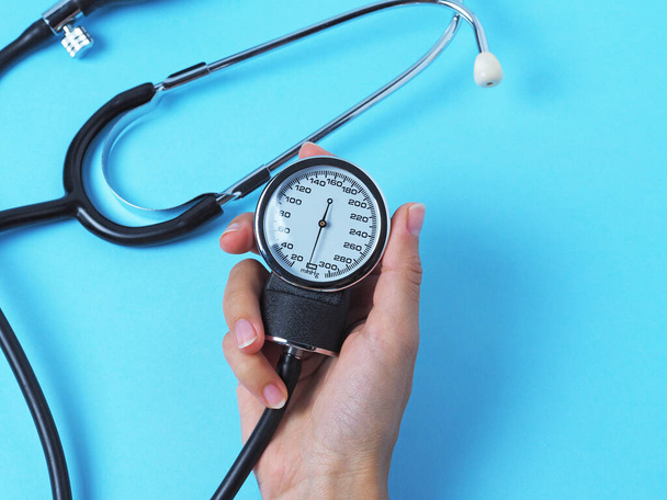 una mano de mujer sostiene un monitor de presión arterial que muestra la presión arterial
 - Foto, imagen