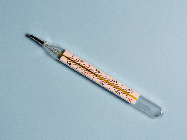 mercury thermometer on a blue background, top view. Tool for changing the temperature of patients - 写真・画像