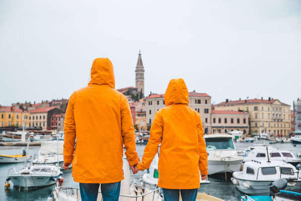 ロヴィニ港の嵐の天気で歩く黄色いレインコートのカップル。コピースペース - 写真・画像