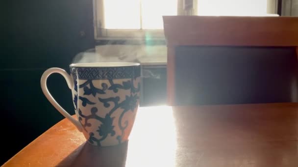 Fényképezés alacsony fényű kávésbögrében füsttel a fa asztalon, napfénnyel. - Felvétel, videó