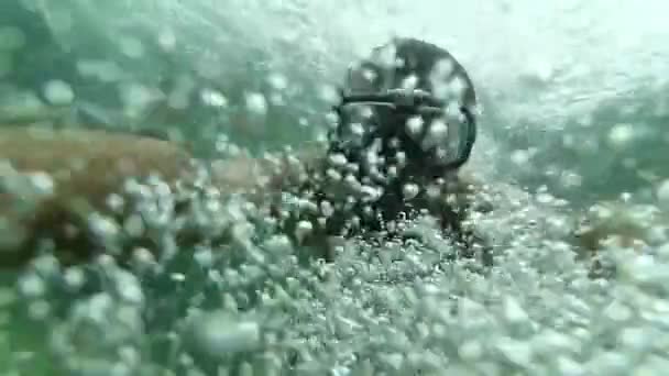 Twarz nurka nurkującego w masce z rurką pod wodą. Wolno poruszające się podwodne selfie wśród pęcherzyków powietrza. - Materiał filmowy, wideo
