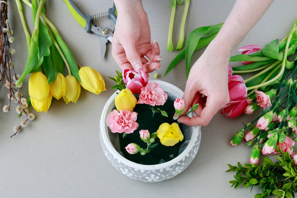 Florist at work: woman shows how to make beautiful floral arrangement with tulip and carnation flowers. Easter home decoration. Step by step, tutorial. - Foto, Imagen