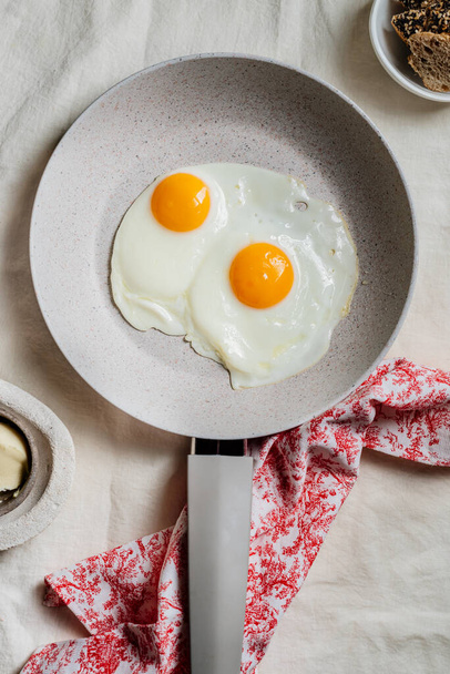 Яйцо. вид двух жареных яиц на сковородке. готовый к употреблению в пищу с завтраком или обедом
 - Фото, изображение