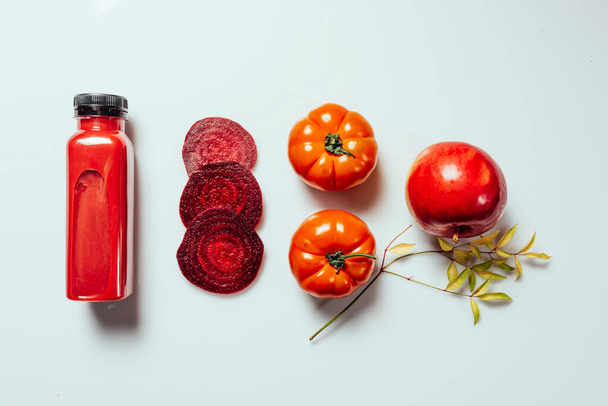 Bebida de batido rojo en botella cerca de manzanas maduras tomates y remolachas. Dieta de desintoxicación para el cuerpo y la mente sanos. concepto de alimentos saludables. Sobre fondo claro - Foto, Imagen