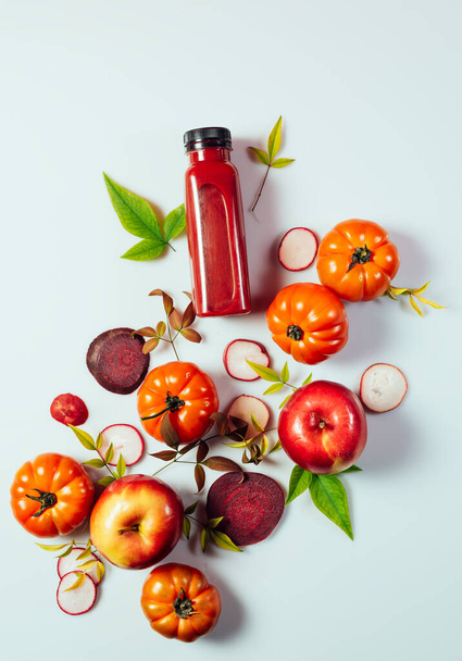 Bebida de batido rojo en botella cerca de manzanas maduras tomates y remolachas. Dieta de desintoxicación para el cuerpo y la mente sanos. concepto de alimentos saludables - Foto, Imagen