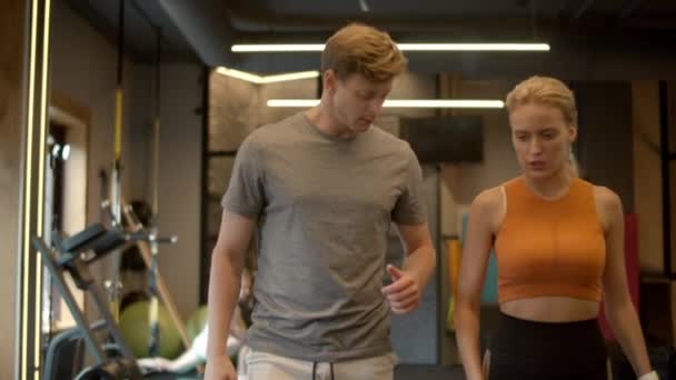 Χαρούμενο ζευγάρι που περπατάει στο γυμναστήριο. Αθλητισμός άνδρας και γυναίκα μιλώντας σε αθλητικό σύλλογο - Πλάνα, βίντεο