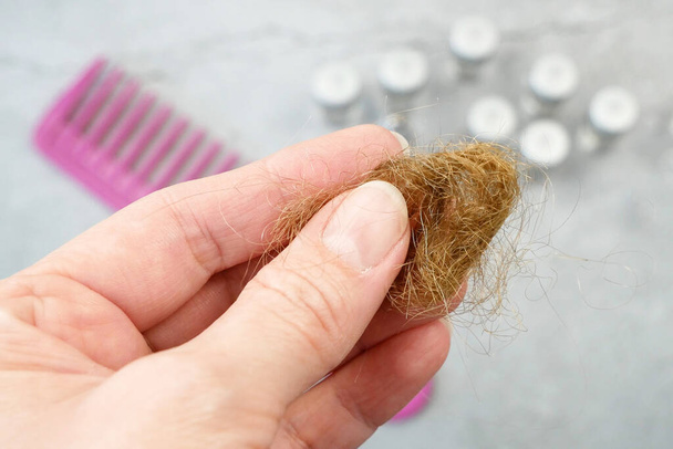 hair loss problem. Bottles with medicine, hairbrush and hair bun. alternative treatments medication bottles and comb on gray background - Photo, Image