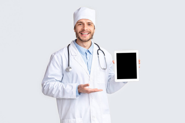 Friendly doctor showing digital tablet with blank screen - Fotoğraf, Görsel
